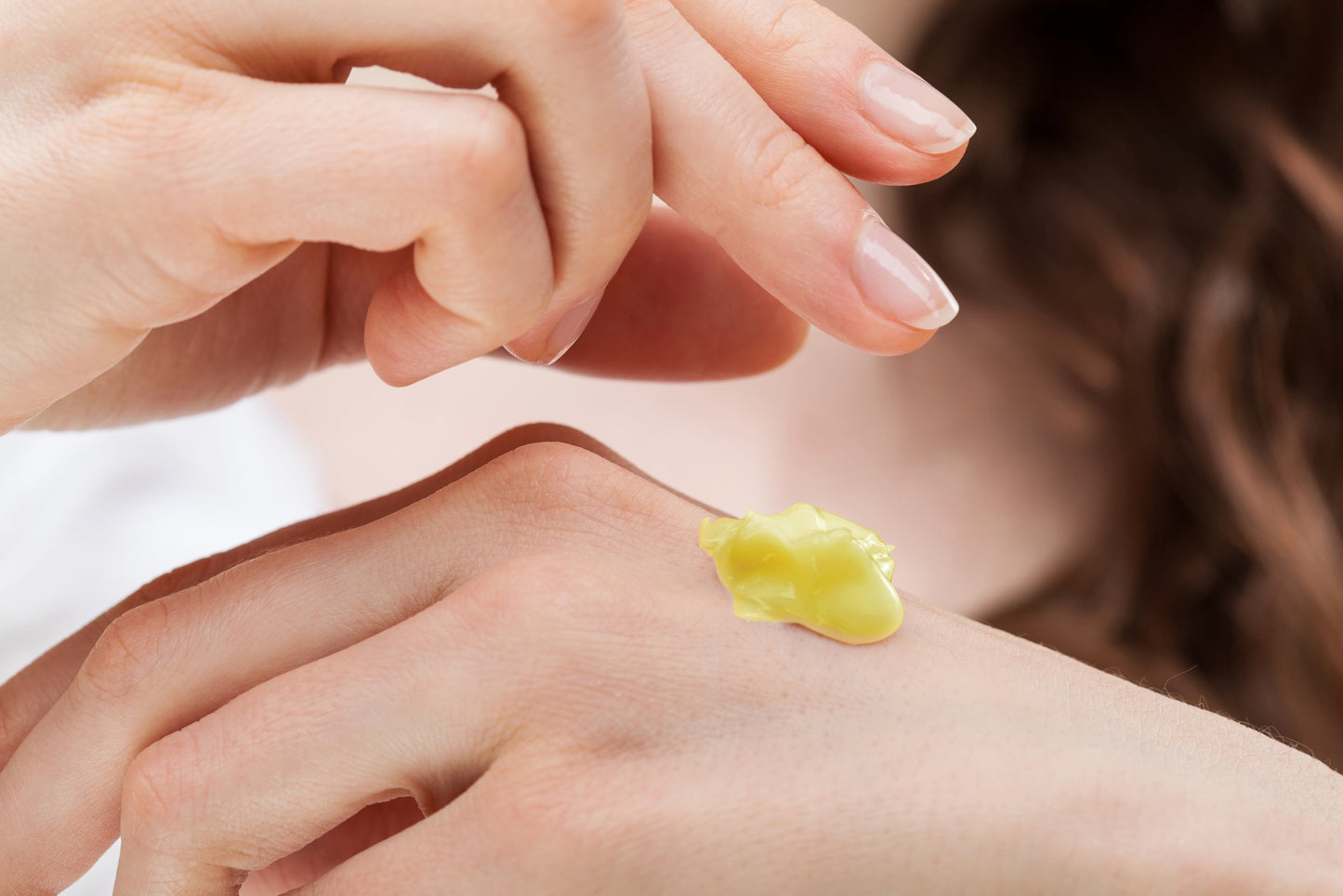 NuBalm women's personal lubricant and massage balm on women's hand